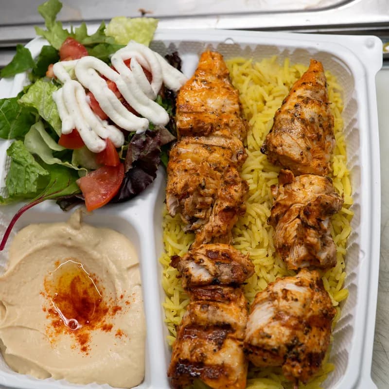 A Green Olive chicken kebab plate with hummus, yellow rice and house salad