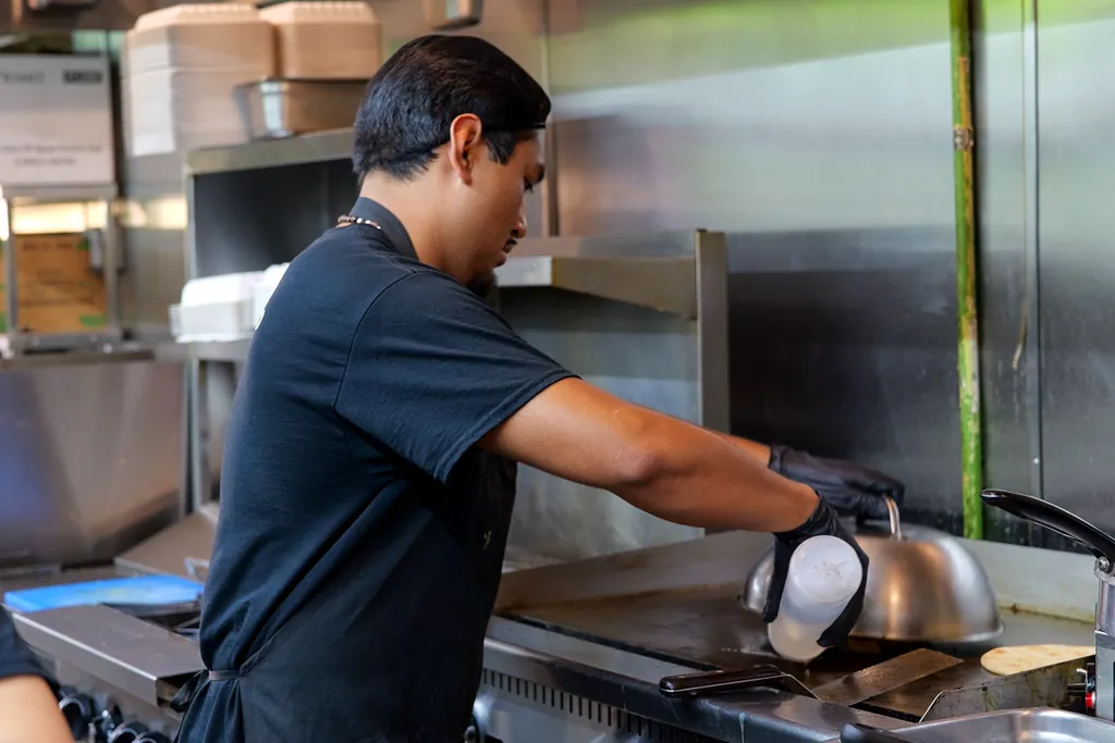A Green Olive cook working the grill line