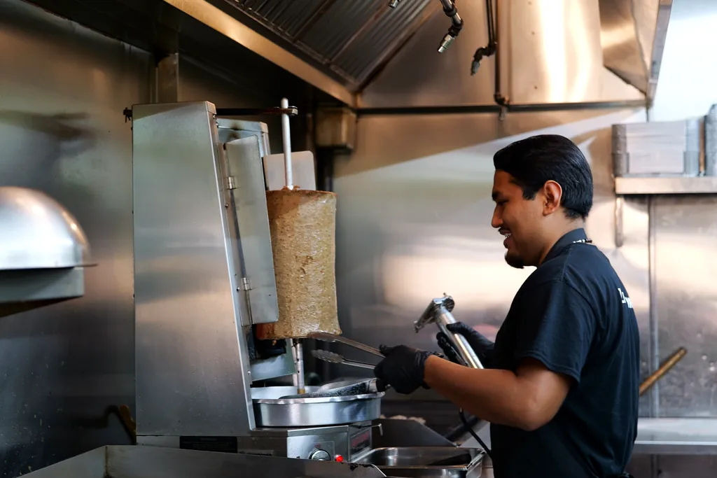 A smiling Green Olive cook at the gyro station